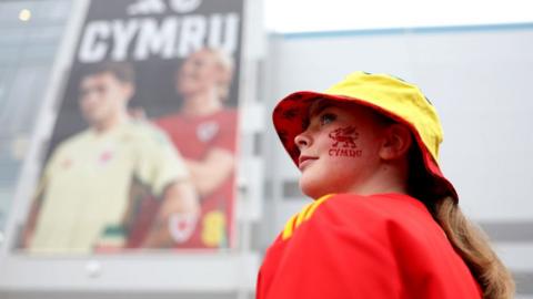 A Wales fan poses for a photo outside the ground