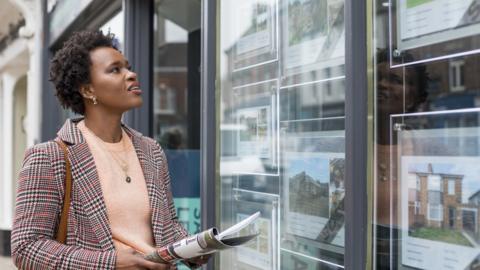 Woman looking in estate agent window