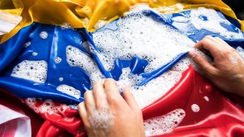 Model's hands washing a Colombian flag