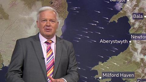 Derek Brockway in front of a weather map