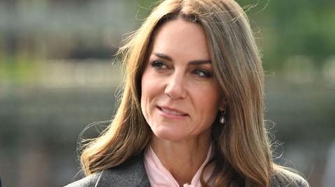 A head and shoulders crop of Catherine, Princess of Wales, as she looks to the left of frame against an out-of-focus background as she stands outside during a visit to Farnborough Road Infant and Junior School in Birkdale in September.