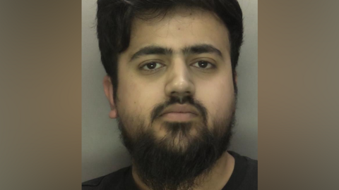 Police mugshot of Ehsan Hussain looking at the camera, wearing a black t-shirt