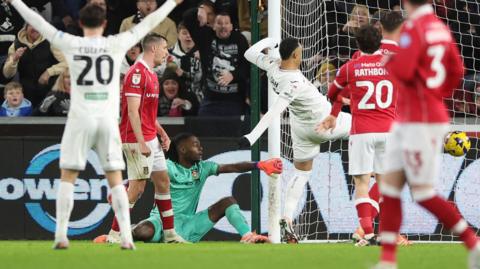 Arthur Okonkwo (in green) drops the ball and allows Adam Idah to score for Swansea