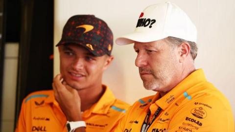 Zak Brown and Lando Norris stand in the McLaren garage