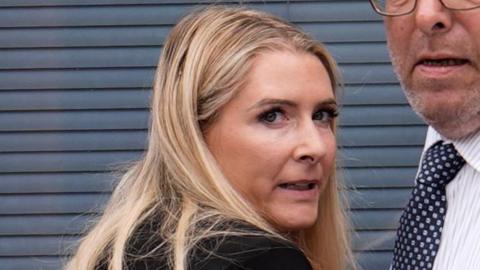 A blonde woman looking over her shoulder at the camera.