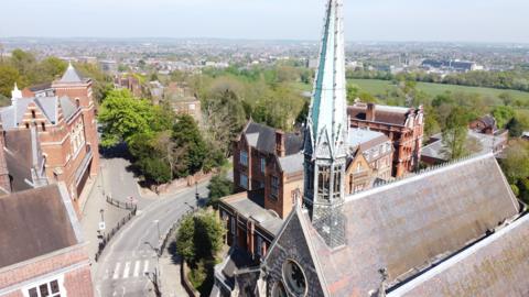 A building with large green spire can be seen in the foreground, with views across large parts of residential north west London in the background