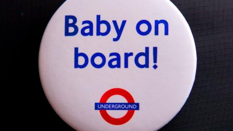 A white button badge with the words "Baby on board!" in blue, written above the London Underground logo.