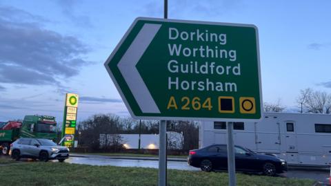 A road sign. It shows the towns of Dorking, Worthing, Guildford and Horsham. 