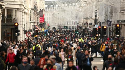 Crowds fill a pedestrianised Regent Street, walking under street decorations of angels installed for Christams