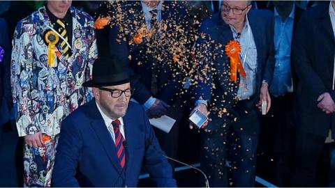 Orange confetti being thrown at George Galloway