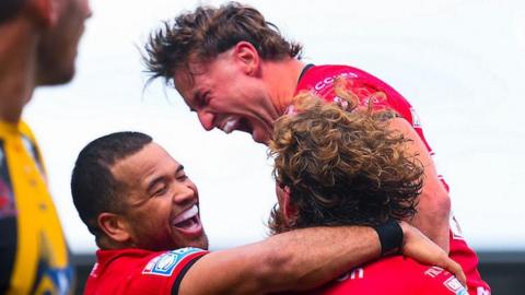 Salford Red Devils player Joe Mellor shouts in celebration and is embraced by teammates after scoring a try against Castleford Tigers.