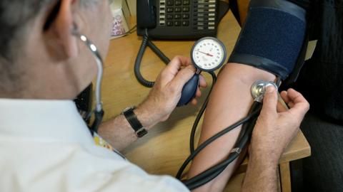 GP taking a patient's blood pressure