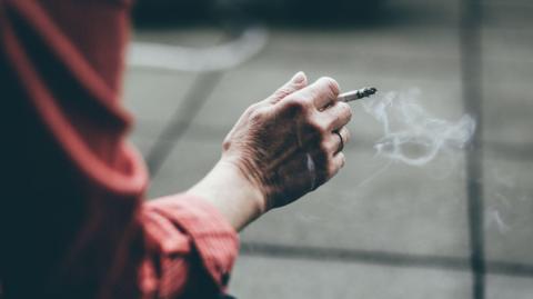A stock image of someone's hand holding a cigarette.