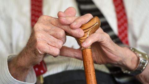 File photo of an elderly man holding a wooden walking stick