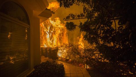 Flames approach a house during the Woolsey Fire on November 9, 2018 in Malibu, California