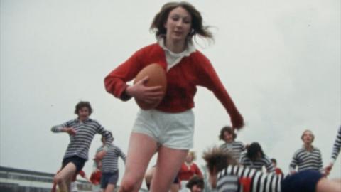 Woman runs with the rugby ball in her arms