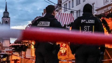 Two German police officer stand behind red and white police tape by the Christmas markets