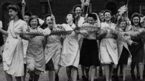 Women dance jubilantly waving Union flags 