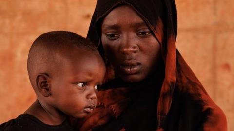 Kobra Yagoub-Sharaf with her daughter Eldin from Darfur pose for a portrait on the Chad Sudan border after having their documents processed on 20 April.