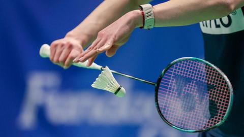 Badminton player serves a shuttlecock