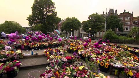 A sea of flowers, balloons and tributes placed on a public square