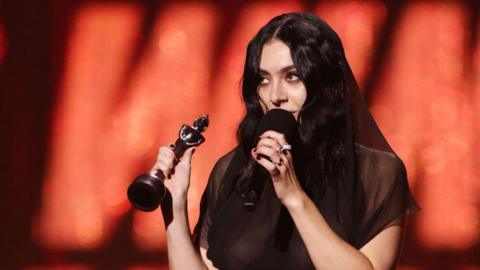 Charlie XCX holding Brit award. 