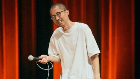 Chizi performs on stage in Taipei in April 2026, wearing a white oversized T shirt and a pair of glasses.
