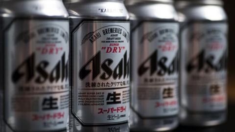 Four silver cans of Asahi beer displayed on a shelf 