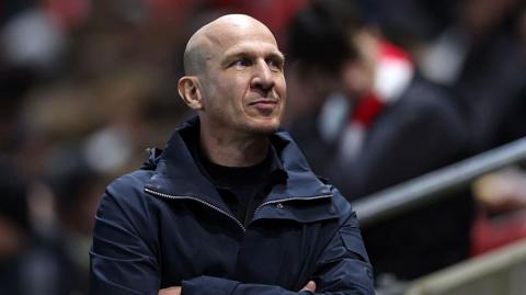 Bristol City boss Gerhard Struber smiles and looks up at the stands while folding his arms on the touchline