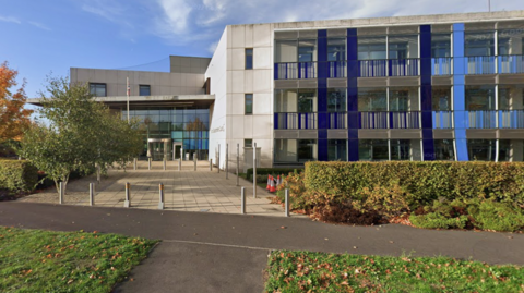 An exterior view of South Gloucestershire Council's headquarters, with some bushes and grass in the foreground