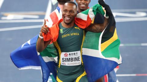 Third placed Akani Simbine of South Africa celebrates with a flag draped around his shoulders after winning bronze in the men's 60m final at the World Athletics Indoor Championships in Nanjing, China