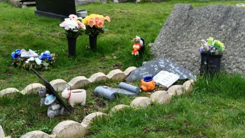 Mass grave for a baby in a Wirral cemetery with artificial flowers and pot animals on it