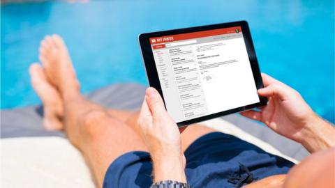 Using a tablet to read emails while sitting by a swimming pool