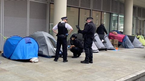 Image showing a female officer bent down talking to someone inside a tent on the street