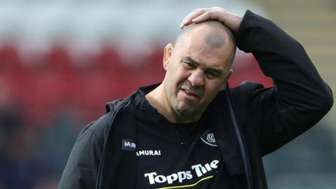 Leicester Tiger's Michael Cheika has his hand on his head while walking off the pitch