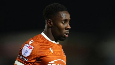 Andy Yiadom looks thoughtful as he stares straight ahead, head and torso shot wearing orange away kit of Reading