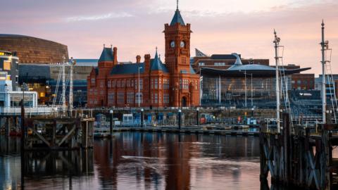 A view of Cardiff Bay, with the waterfront and the Pierhead in the foreground, and the Senedd and the Welsh Millennium Centre to the sides of the picture.