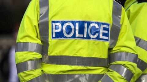 A stock image of a neon yellow police vest with the word "police" written on the back in white letters on blue background.
