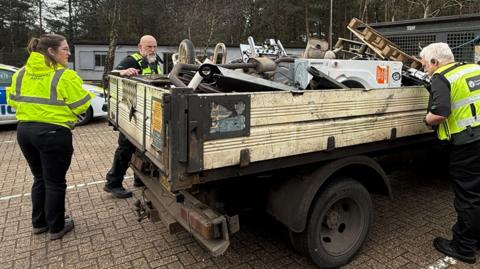A group of people checking the load of a van. 