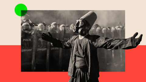 A protester wearing a whirling dervish costume performs in front of Turkish riot police barricades
