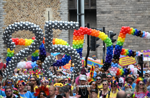 Balloons in silver denoting 25, and then rainbow balloons saying Pride, with loads of people walking through town centre