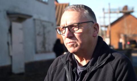 A man stands in front of a pub.