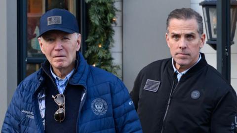 US President Joe Biden and his son Hunter Biden step out of a bookshop in Nantucket, Massachusetts on 29 November. Joe Biden wears a navy cap, fleece and puffer coat, while Hunter wears a jacket. 