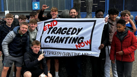 Cefnogwyr Peldroed yn dal baner anferth 'End Tragedy Chanting now'