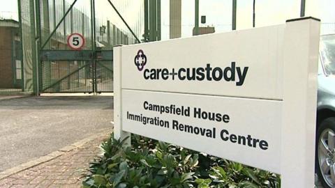 A sign saying Campsfield House Immigration Removal Centre in front of a green metal gate