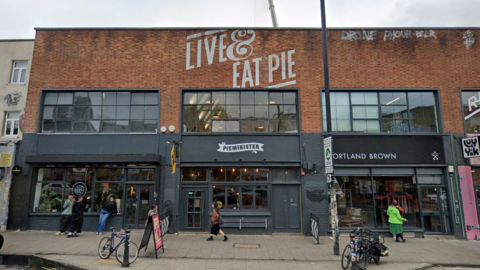 Pieminister in Bristol. The building is red brick with Live & Eat Pie painted at the top. The storefront is black with a white Pieminister logo above the door. 