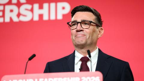 Andy Burnham smiling and standing in front of a red backdrop as the newly announced leader of the Labour Party makes, his first speech to party members in central London on July 17, 2026 in London, England.