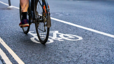 Someone riding a black bike in a cycle lane.
