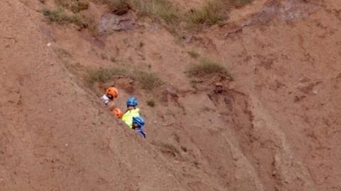 coastguard crew rescuing a man and a woman from Filey Brigg in North Yorkshire