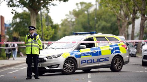 Police officer next to car patrolling cordon
